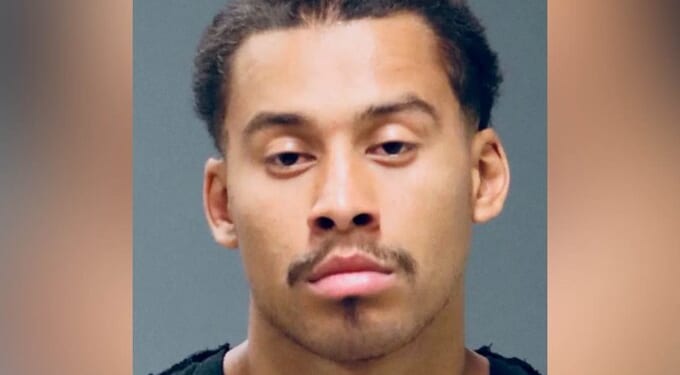 Mugshot of a young man with short hair and a mustache, displaying a serious expression against a neutral background.