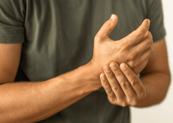Person experiencing wrist pain while holding their wrist with one hand, indicating discomfort or injury.