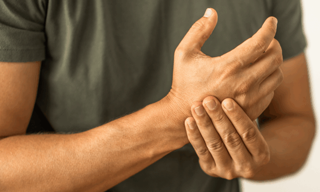 Person experiencing wrist pain while holding their wrist with one hand, indicating discomfort or injury.