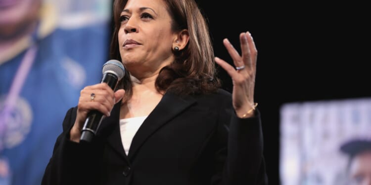 Kamala Harris speaking passionately into a microphone during a public event, emphasizing key points with hand gestures.
