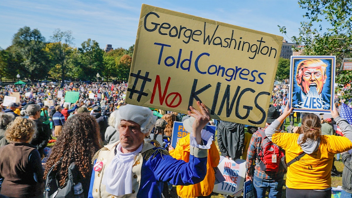 A man dressed as former U.S. President George Washington displays a sign during a "No Kings" protest against U.S. President Donald Trump's policies in Boston, Mass., Oct. 18, 2025.