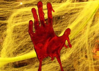Red handprint on a yellow spider web background, creating a spooky atmosphere suitable for Halloween decorations.