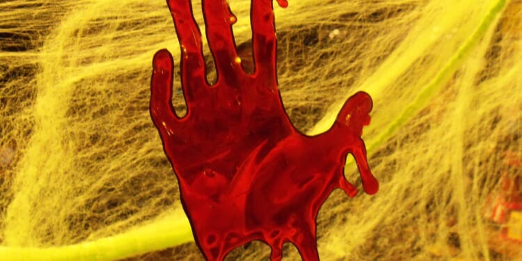 Red handprint on a yellow spider web background, creating a spooky atmosphere suitable for Halloween decorations.