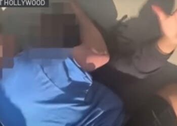 Two individuals interacting on the ground in West Hollywood, with one person appearing to assist the other.