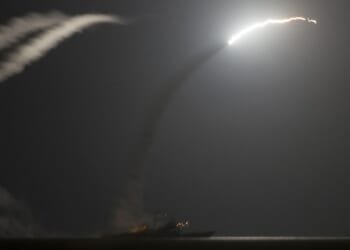 Two Navy ships firing Tomahawk missiles.