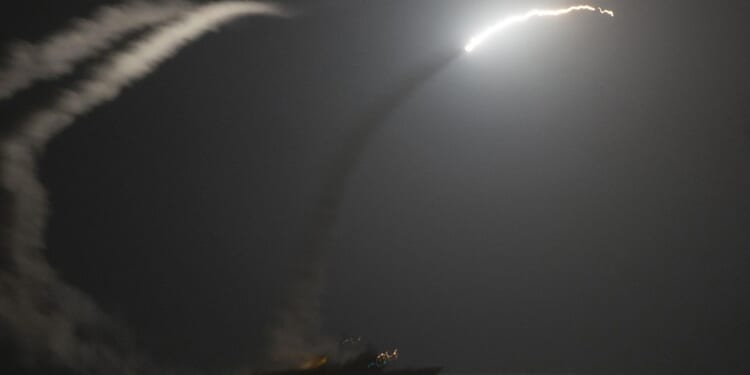 Two Navy ships firing Tomahawk missiles.