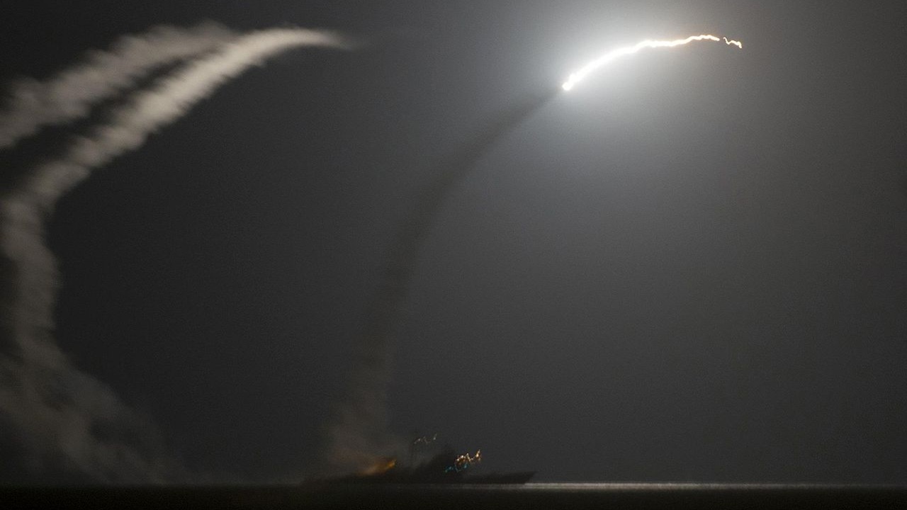 Two Navy ships firing Tomahawk missiles.