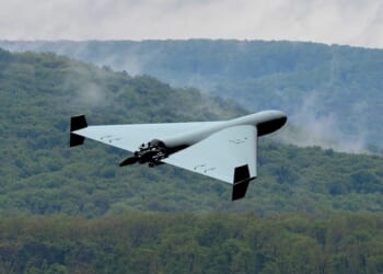 Military kamikaze drone flying over forest in the clouds, Combat drone in the sky, war in Ukraine.