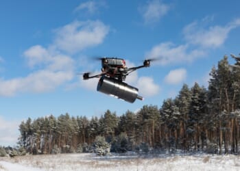 A fiber optic drone emerging from a forest.