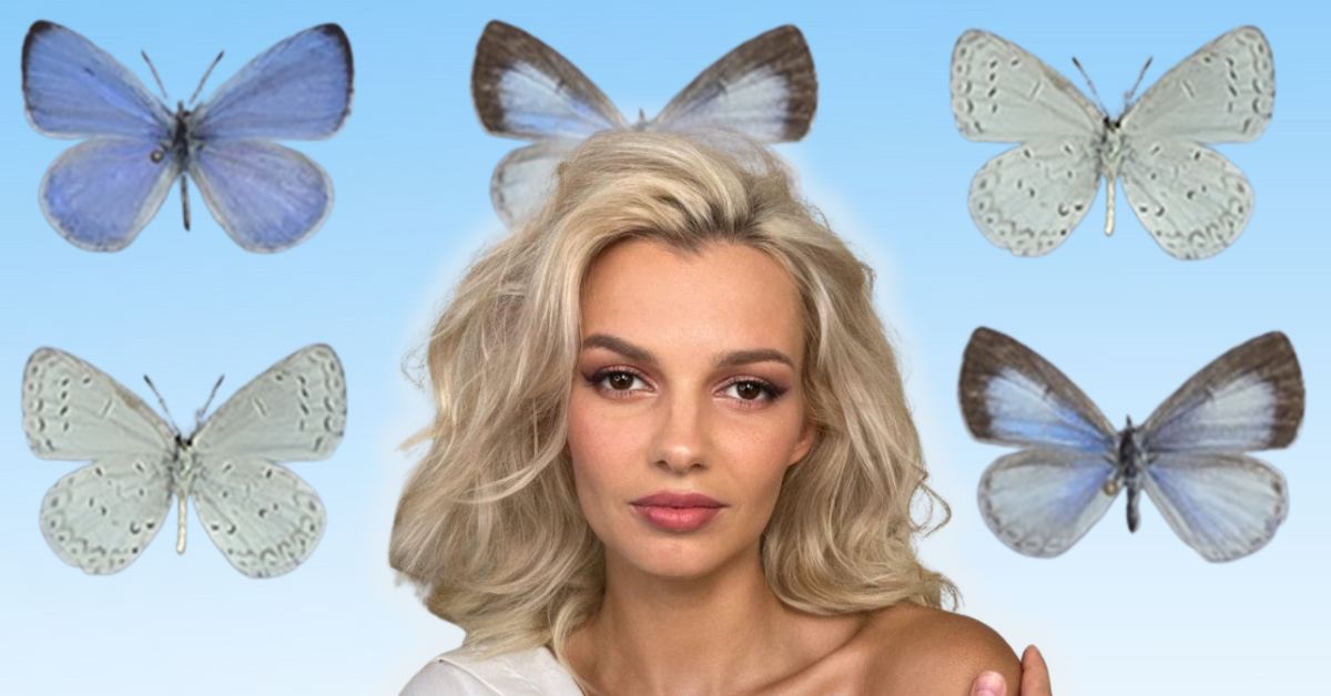 A woman with wavy blonde hair poses against a blue background surrounded by various blue butterflies, creating a whimsical and artistic scene.