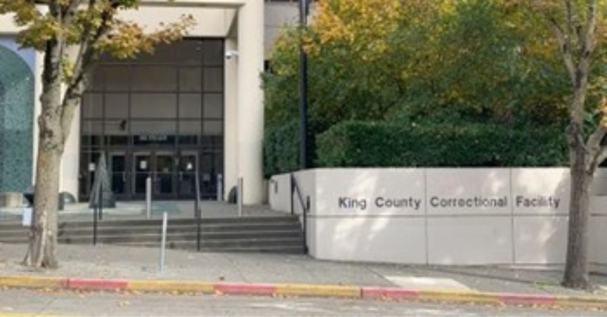 Entrance of King County Correctional Facility showcasing modern architecture and surrounding landscaping in Seattle, Washington.