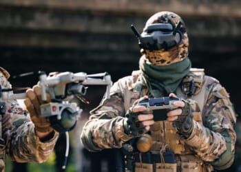 Military soldier operator UAV controls drone with device for releasing mines and grenades to enemy positions. Concept using robot in smart war.