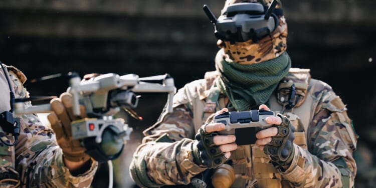 Military soldier operator UAV controls drone with device for releasing mines and grenades to enemy positions. Concept using robot in smart war.