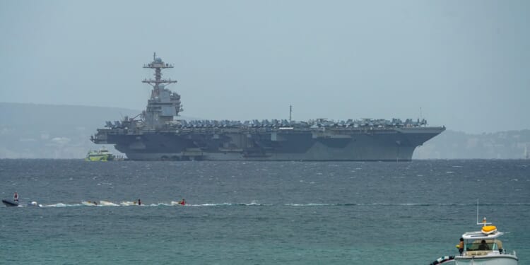 The USS Gerald R. Ford aircraft carrier, seen in the distance.