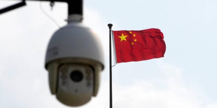 Chinese flag waving in the background with a surveillance camera in the foreground, symbolizing security and monitoring in China.