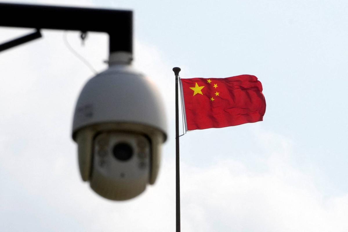 Chinese flag waving in the background with a surveillance camera in the foreground, symbolizing security and monitoring in China.