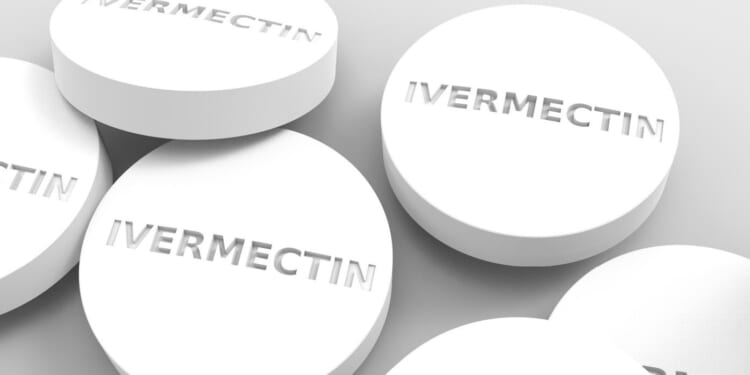 White Ivermectin tablets displayed on a neutral background, highlighting their round shape and embossed lettering.