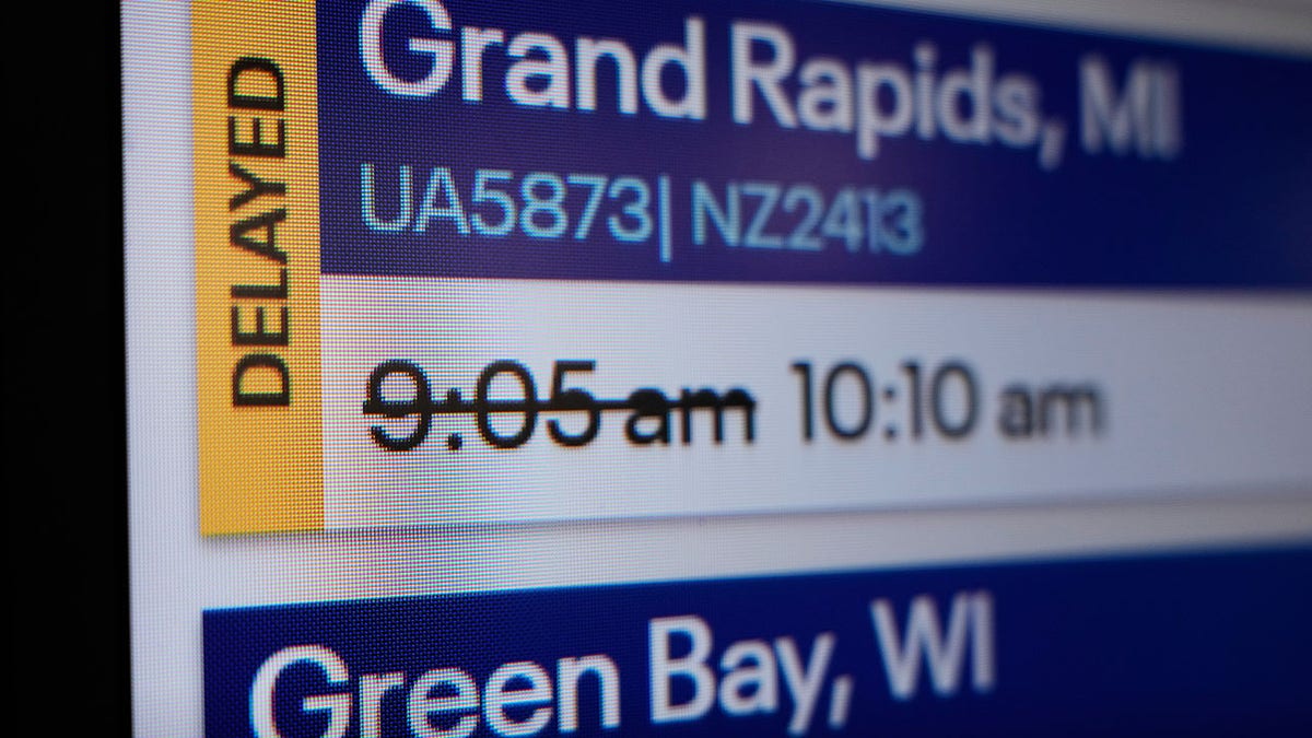 A screen at an airport showing a flight delay.