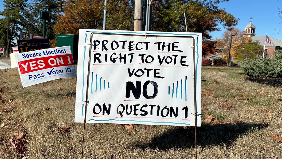 Signs with opposing messages about a Maine voter identification referendum displayed outdoors.