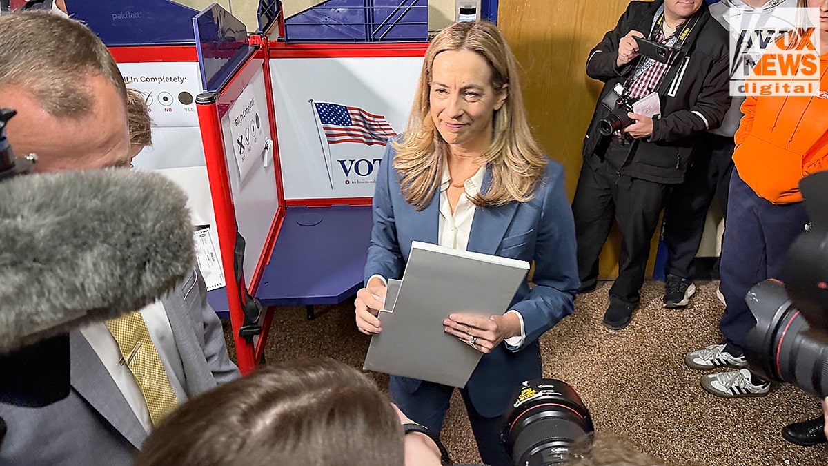 Rep. Mikie Sherrill stands near a voting booth, surrounded by reporters, after casting her ballot in Montclair, New Jersey.