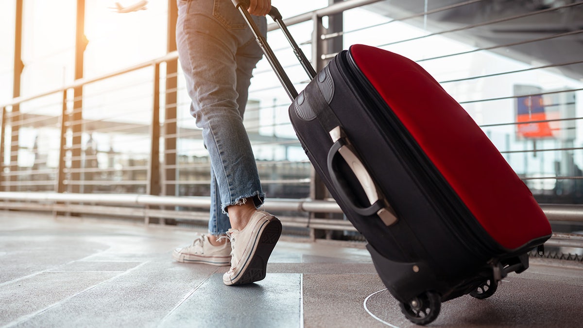 Woman wearing jeans walking with suitcase at airport