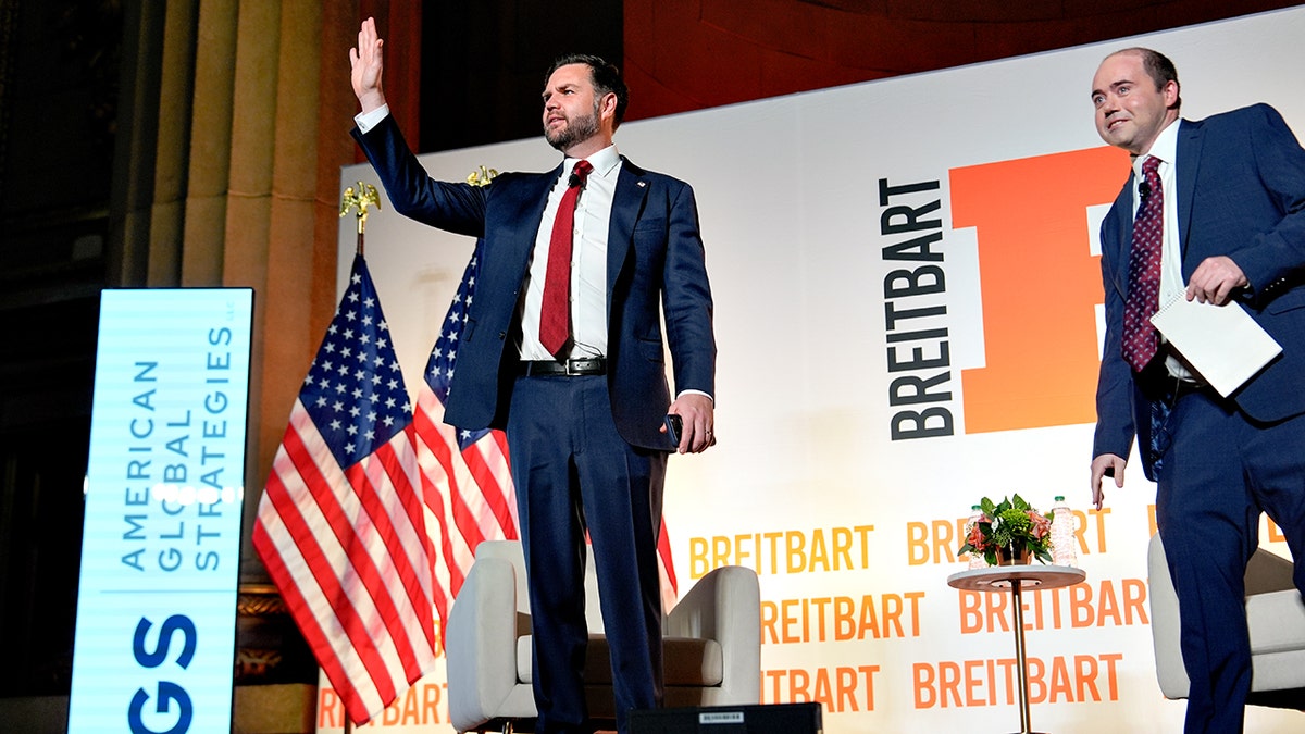 Vice President JD Vance waves while standing on stage