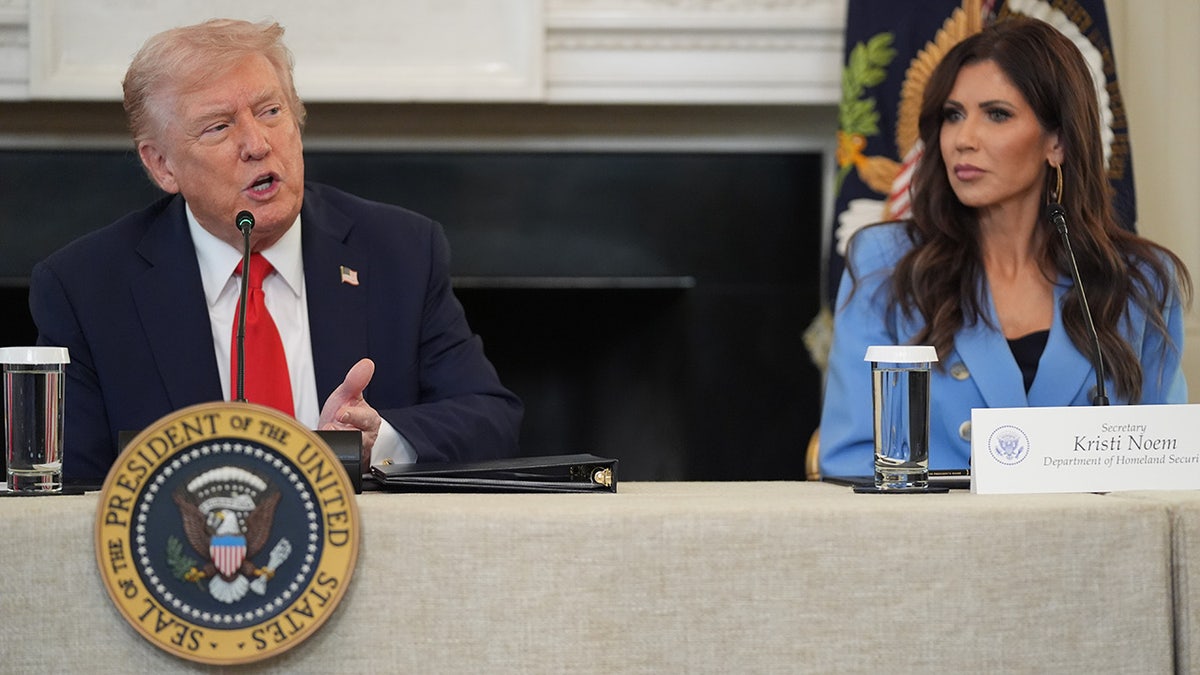 President Donald Trump speaks during a roundtable meeting on antifa in the State Dining Room at the White House, Wednesday, Oct. 8, 2025, in Washington, as Homeland Security Secretary Kristi Noem listens. (AP Photo/Evan Vucci)