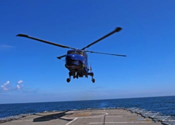 A helicopter landing on an aircraft carrier deck.