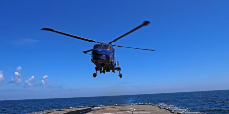 A helicopter landing on an aircraft carrier deck.