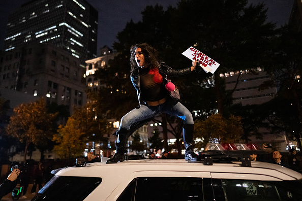 A protestor stands atop an NYPD vehicle