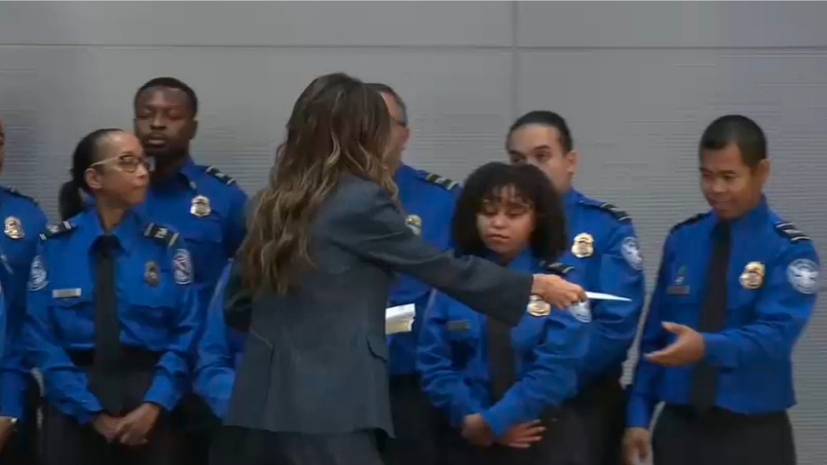 Kristi Noem hands a TSA officer a bonus check