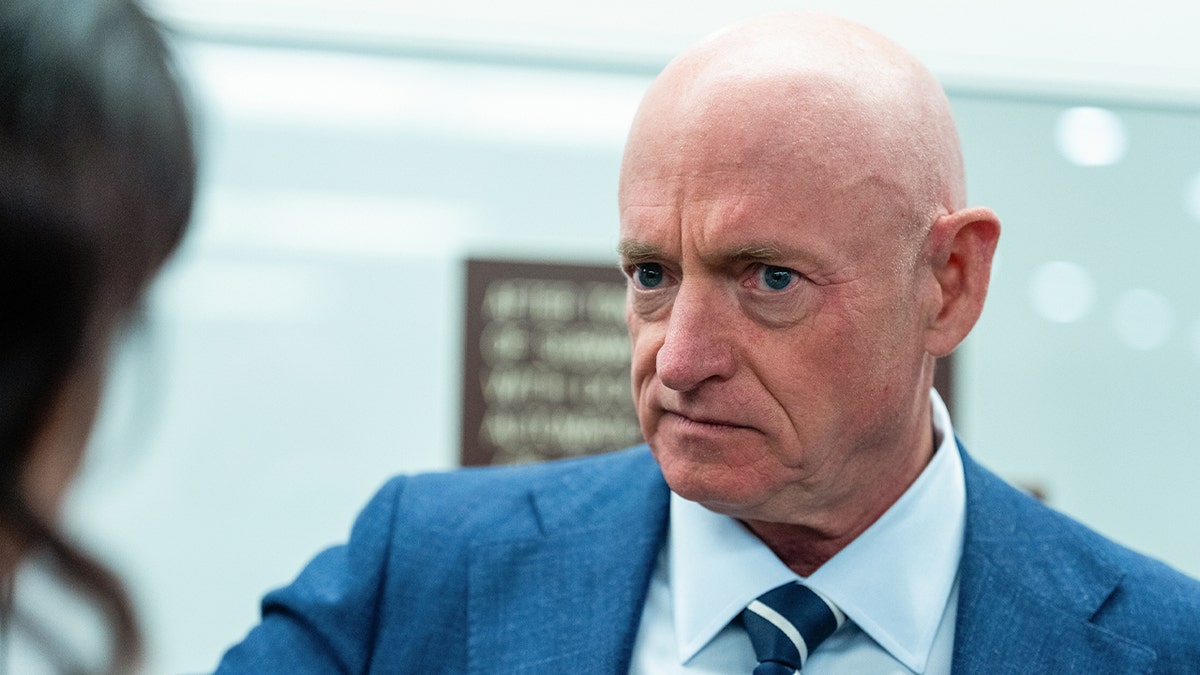 mark kelly in blue suit and striped blue tie looking concerned