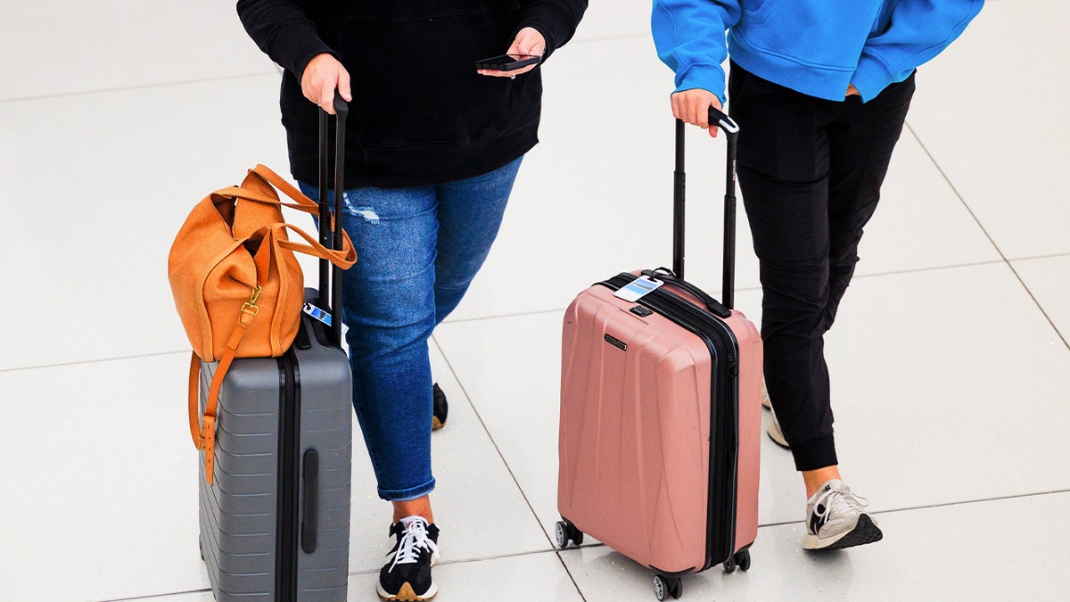 Women roll suitcases through an airport
