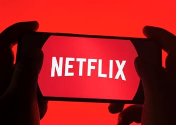 A pair of hands holding a phone with the Netflix logo.