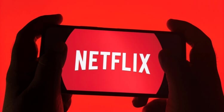 A pair of hands holding a phone with the Netflix logo.