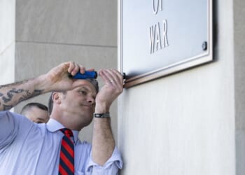 Pete Hegseth screwing a plaque in at the Pentagon.