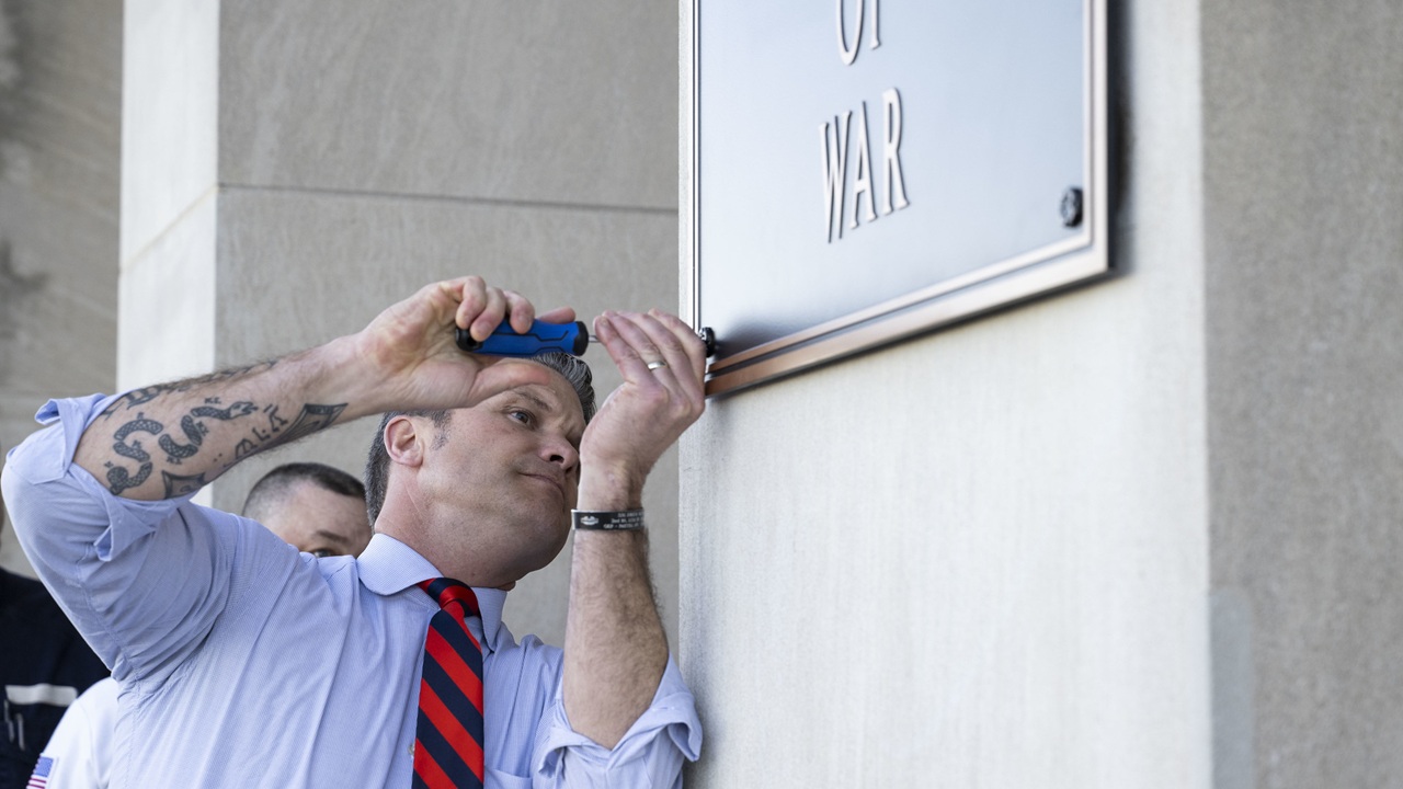 Pete Hegseth screwing a plaque in at the Pentagon.