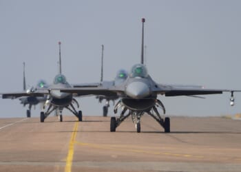 A line of F-16 fighter jets taking off.