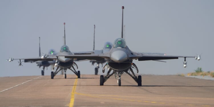 A line of F-16 fighter jets taking off.