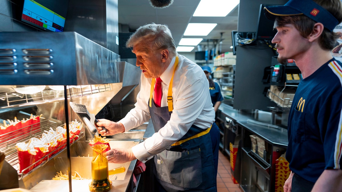 President Donald Trump, left, uses a fryer as an employee looks on during a visit to McDonald's in Feasterville-Trevose, Pa., Sunday, Oct. 20, 2024.