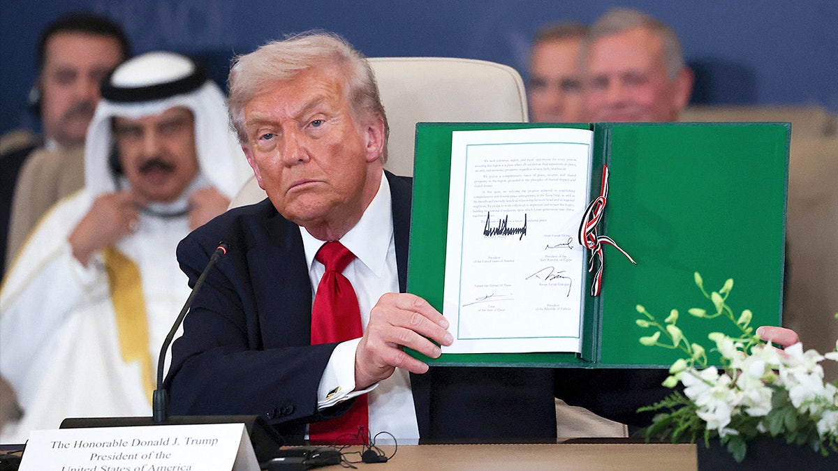 Donald Trump holds up a signed agreement while posing for photos
