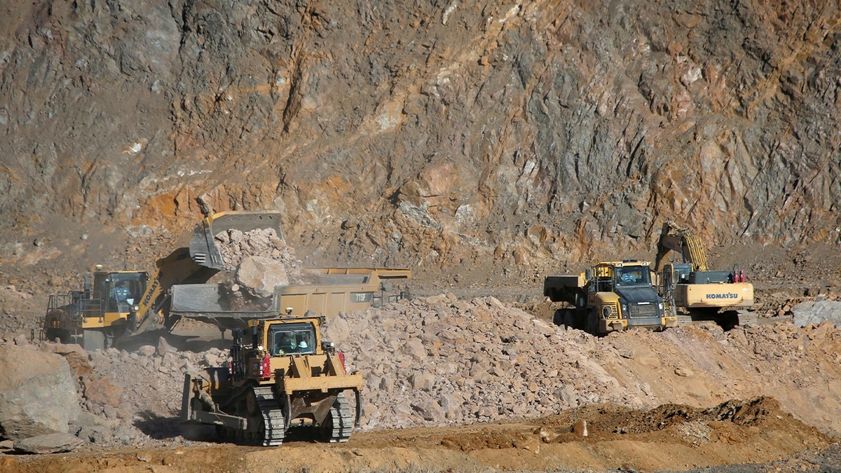 Wheel loaders fill trucks with ore at the MP Materials rare earth mine in Mountain Pass, California