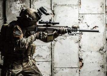 Army Ranger moving along the concrete wall on mission.