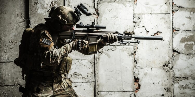 Army Ranger moving along the concrete wall on mission.