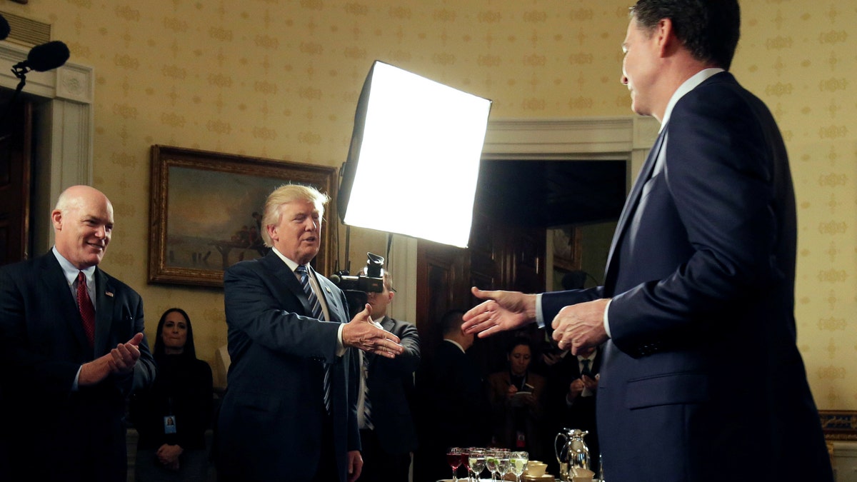 U.S. President Donald Trump greets Director of the FBI James Comey as Director of the Secret Service Joseph Clancy (L) watches during the Inaugural Law Enforcement Officers and First Responders Reception in the Blue Room of the White House in Washington, U.S., January 22, 2017. REUTERS/Joshua Roberts - RTSWV5T