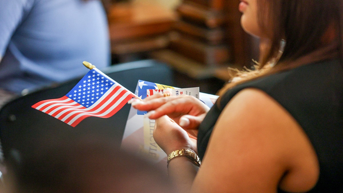 U.S. citizenship ceremony attendee holds a flag on her lap
