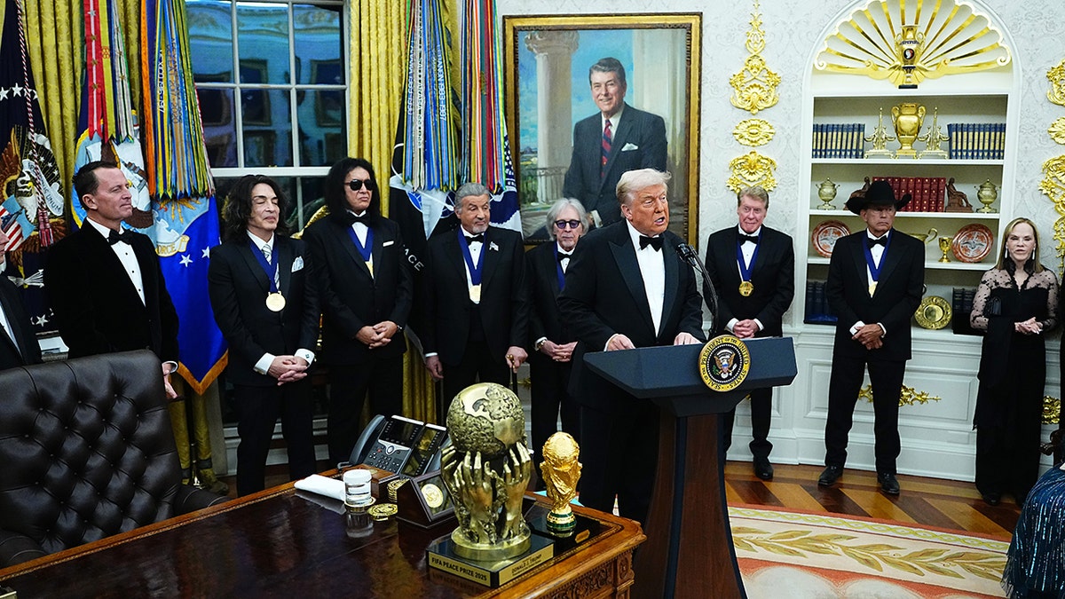 President Trump speaks at podium in Oval Office with Kennedy Center Honors recipients