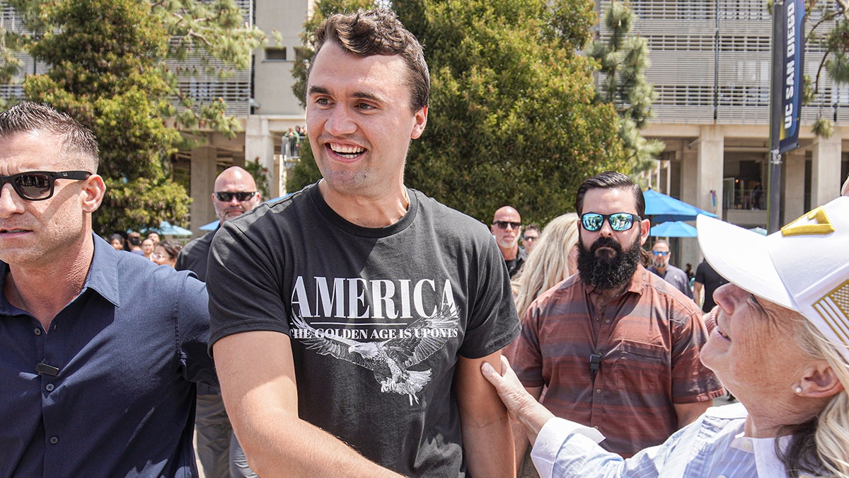 Charlie Kirk smiling as he greets supporters.