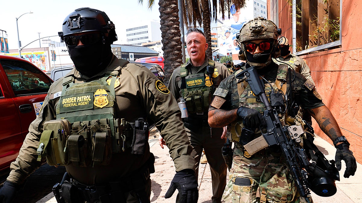 Commander of Operation At Large CA marches with federal agents toward the Edward R. Roybal Federal Building
