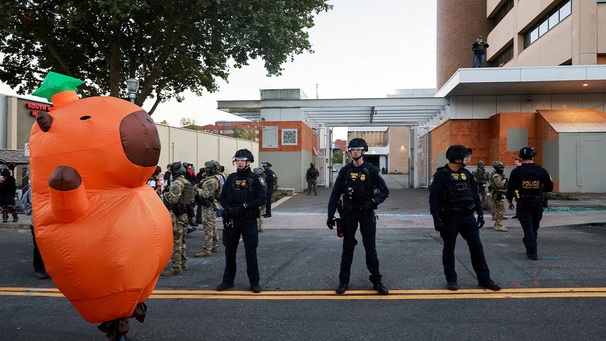 A demonstrator wearing an inflatable Capybara costume stands outside of the U.S. Immigration and Customs Enforcement (ICE) headquarters, as police work to disperse the crowd to clear traffic driving into the ICE building, during a protest, in south Portland, Oregon, U.S., October 6, 2025.
